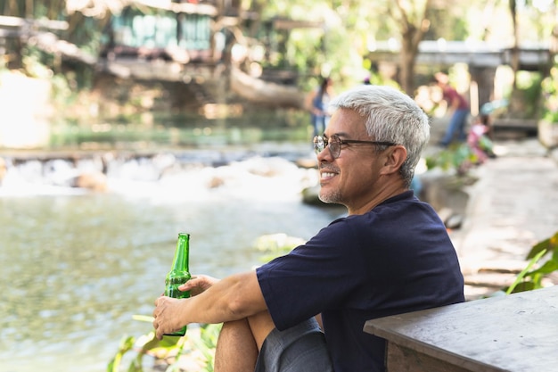 Homem feliz com um sorriso na mão segurando uma garrafa