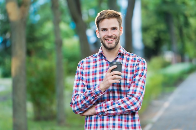 Homem feliz com uma xícara de café na rua usa pessoas, bebidas e camisa quadriculada.