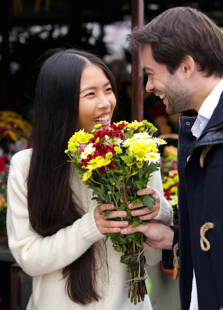 Homem feliz dando flores a mulher sorridente