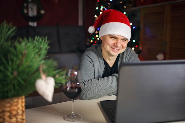 Homem feliz de natal online com chapéu de papai noel vermelho comemorando com a família virtualmente via internet