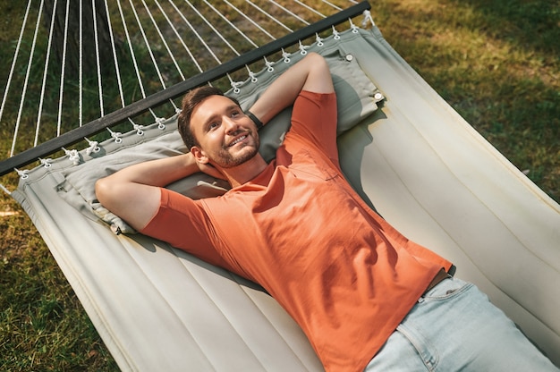 Homem feliz deitado a pensar numa rede na natureza