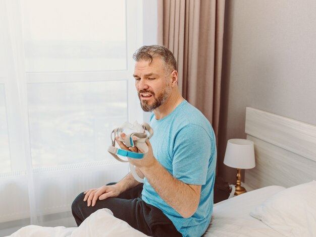 homem feliz e descansado com problemas respiratórios crônicos após usar a máquina de cpap sentado na cama