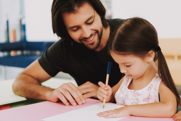 Homem feliz e filha desenhar na clínica pediátrica