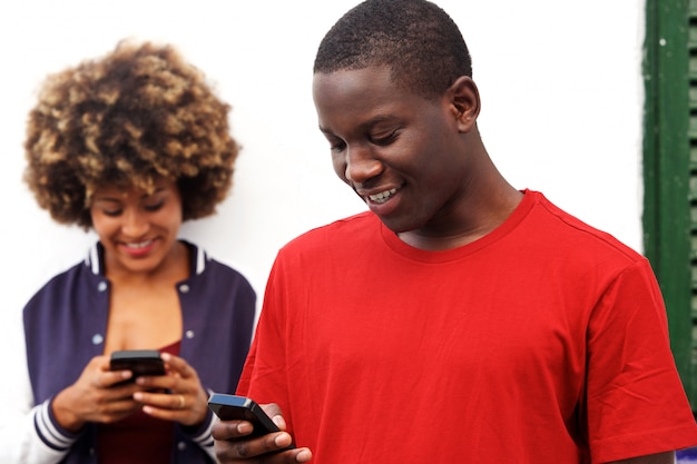 Homem feliz e mulher usando telefones celulares ao ar livre