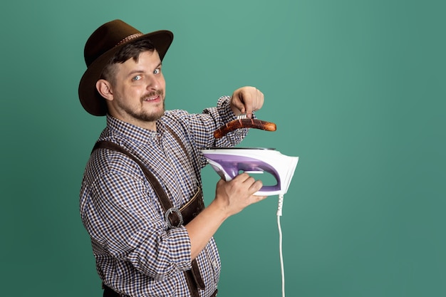 Homem feliz e sorridente, vestido com o traje tradicional austríaco ou bávaro, sentado à mesa com comida festiva e cerveja isolada sobre fundo vermelho