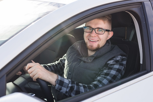 Homem feliz elegante atraente em um bom carro branco.