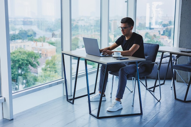 Homem feliz em óculos ópticos para correção de visão procurando informações engraçadas em redes sociais usando conexão sem fio no conceito de tecnologia netbook