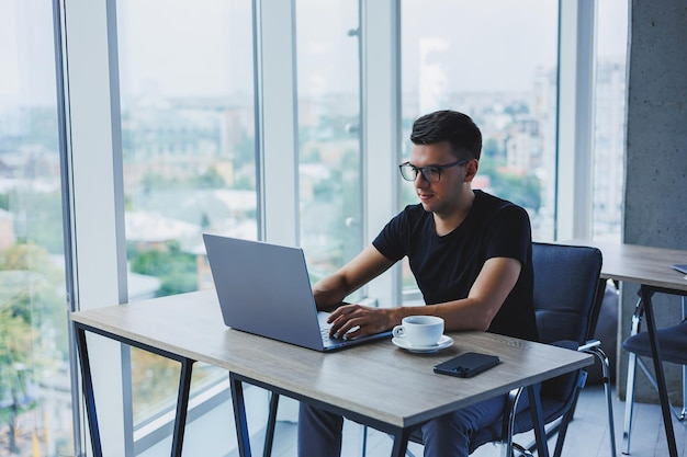 Homem feliz em óculos ópticos para correção de visão procurando informações engraçadas em redes sociais usando conexão sem fio no conceito de tecnologia netbook