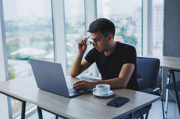 Homem feliz em óculos ópticos para correção de visão procurando informações engraçadas em redes sociais usando conexão sem fio no conceito de tecnologia netbook