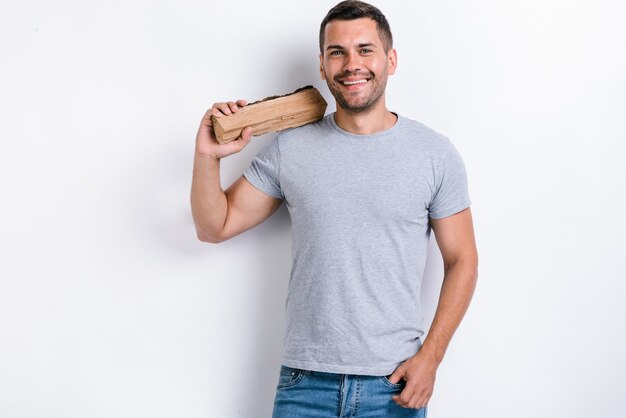 Homem feliz em pé sobre o fundo branco do estúdio e segurando uma lenha no ombro. imagem de estúdio, isolada no fundo branco