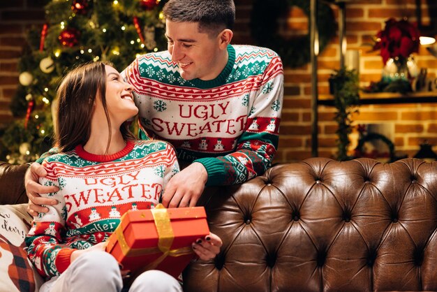 Homem feliz fazendo presente de Natal para sua amada mulher está surpresa e animada