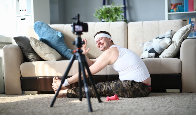 Homem feliz gravando exercício de alongamento na câmera