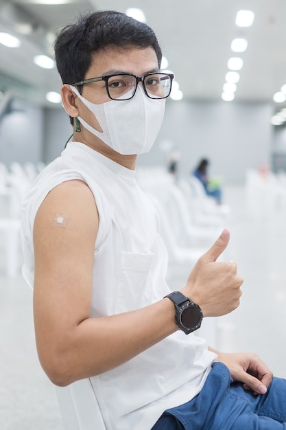 Homem feliz mostrando o polegar após receber a vacina. Vacinação, imunização, inoculação e pandemia de Coronavírus (Covid-19)