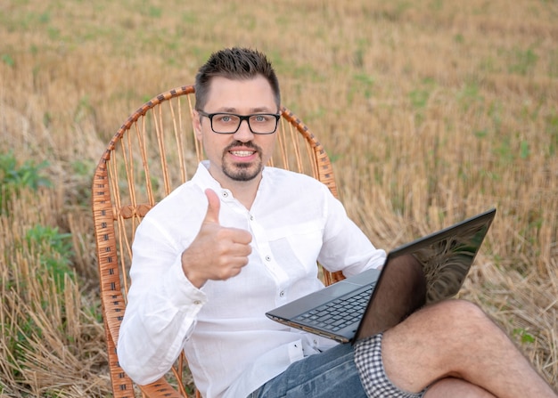 Homem feliz mostrando o polegar para cima e sorrindo, maravilhado por receber boas notícias em mensagens ao ar livre