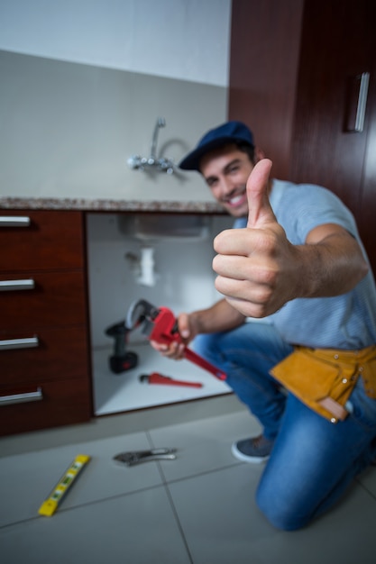 Foto homem feliz, mostrando os polegares, mantendo a chave inglesa