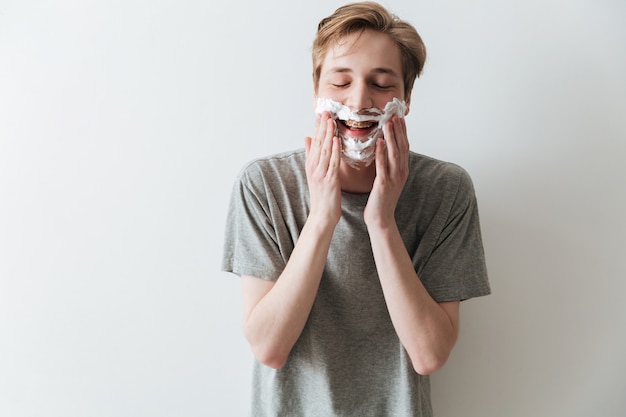 Homem feliz na espuma de barbear, segurando suas bochechas