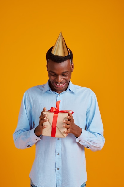 Homem feliz na tampa segurando uma caixa de presente com fitas vermelhas. Homem sorridente tem uma surpresa, evento ou festa de aniversário