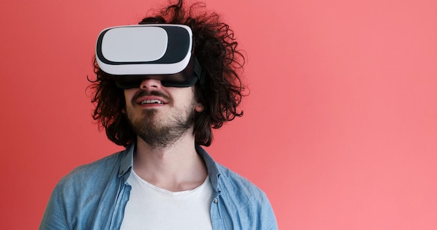 Homem feliz obtendo experiência usando óculos de fone de ouvido VR de realidade virtual, isolados em fundo vermelho