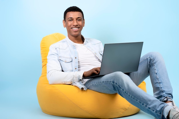 Foto homem feliz olhando para a câmera digitando conteúdo de informações usando laptop para trabalhar