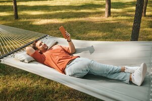 Homem feliz relaxando na rede com tablet