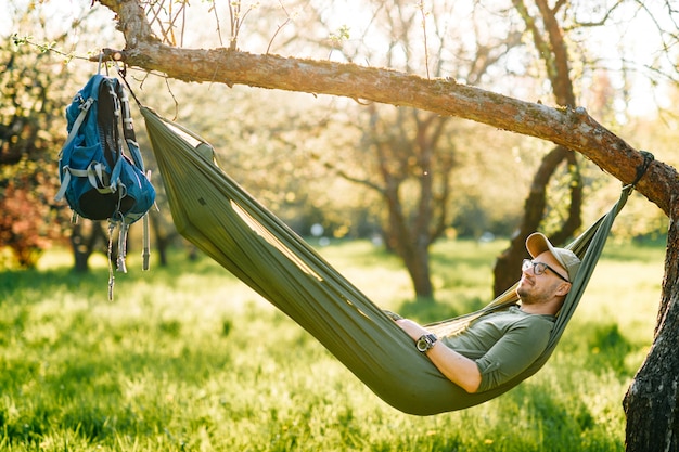 Homem feliz relaxante na rede no parque ensolarado