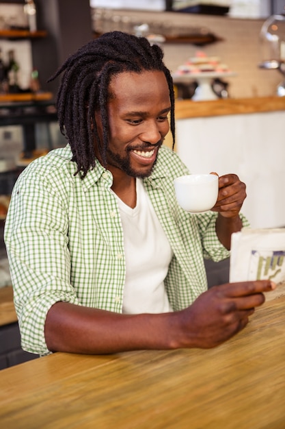 Homem feliz rindo quando está lendo um jornal