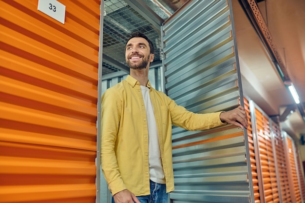 Homem feliz saindo da porta do contêiner do armazém