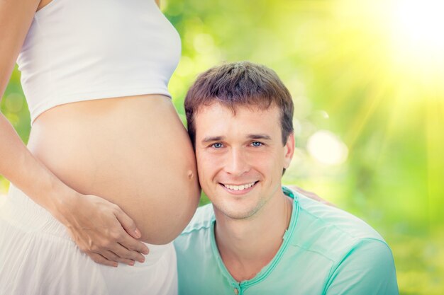 Homem feliz segurando a barriga de uma mulher grávida Família se divertindo ao ar livre no parque primavera.