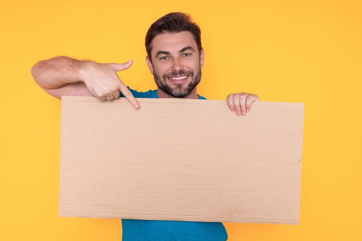 Foto homem feliz segurando o tabuleiro vazio e apontando o dedo a bordo do cara mostrando o tabuleiro em branco com id copyspace