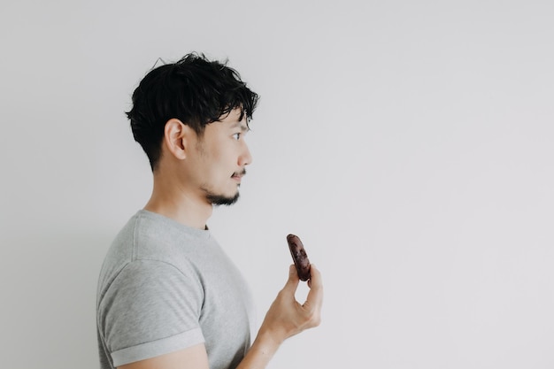 Homem feliz segurando um biscoito de chocolate isolado no fundo branco