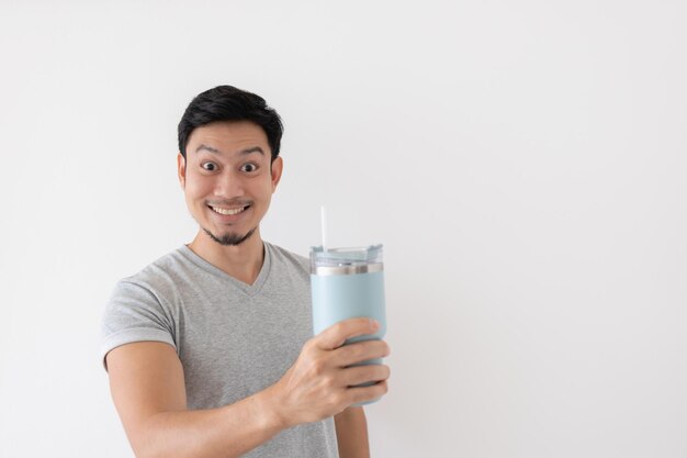 Homem feliz tem bebida gelada da caneca térmica isolada no fundo branco