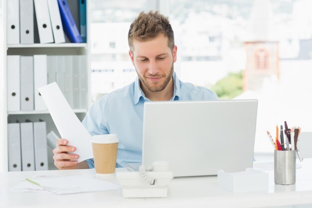 Homem feliz trabalhando em sua mesa no laptop