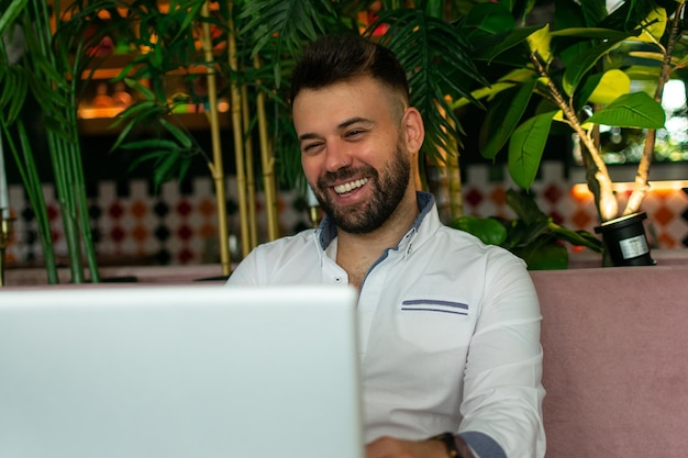 homem feliz trabalhando na cozinha e rindo enquanto olha para laptop turva