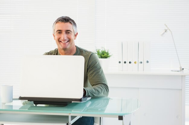 Homem feliz usando seu laptop na mesa