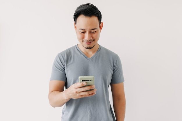 Homem feliz usando smartphone isolado na parede branca