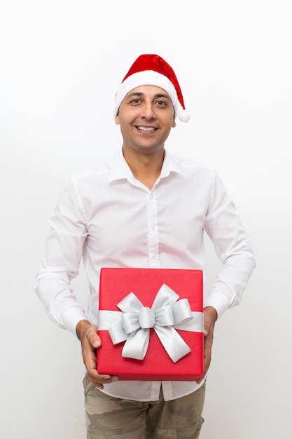 Homem feliz vestindo chapéu de papai noel e segurando caixa de presente