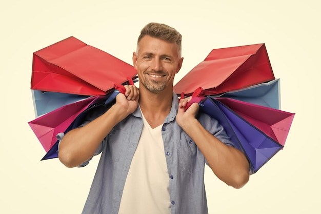 Foto homem feliz viciado em compras ávido com pacotes depois de fazer compras homem bonito cuida de sacolas de compras pesadas comprar presentes e presentes obrigado por sua compra comprador masculino de felicidade de compras isolado no branco