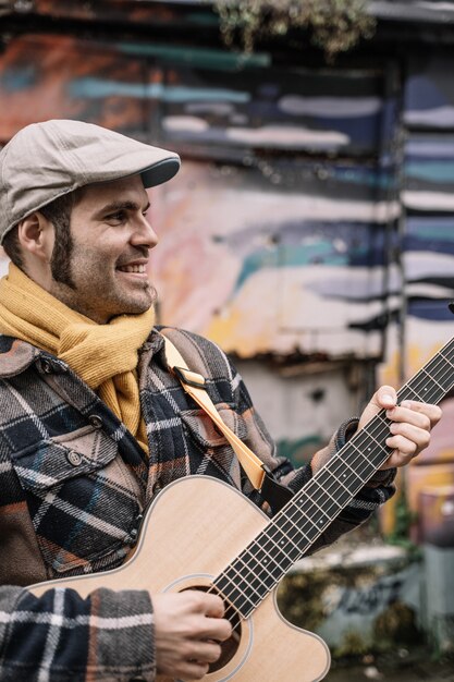 Foto homem fica na rua e toca violão.