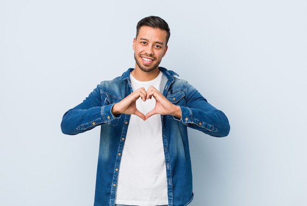 Homem filipino bonito jovem sorrindo e mostrando uma forma de coração com as mãos.