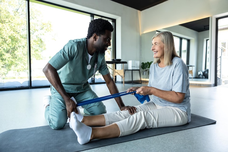 Foto homem fisioterapeuta guiando mulher através de exercício das pernas com banda de resistência para recuperação muscular