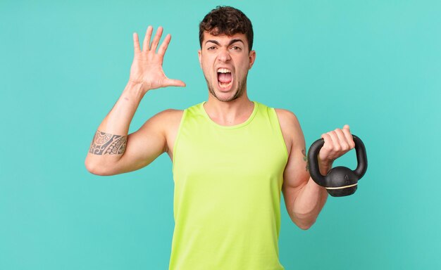 Homem fitness gritando com as mãos no ar sentindo-se furioso frustrado estressado e chateado