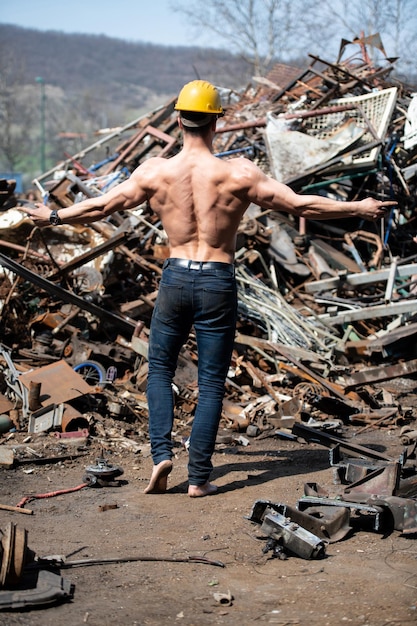 Homem flexionando os músculos no pátio de sucata industrial