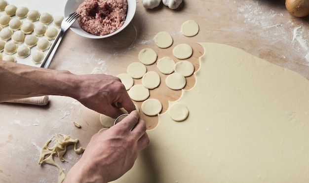 Homem formando pequenos círculos de massa crua, preparando bolinhos de carne. Comida tradicional ucraniana