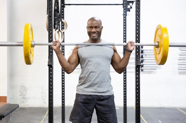 Homem forte afro-americano a levantar pesos. treino corporal no ginásio.