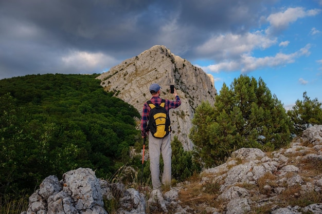 Homem forte alpinista tirando foto com telefone inteligente no pico da montanha