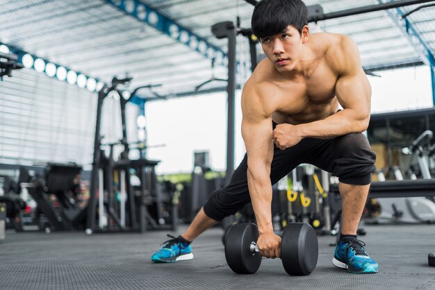 Homem forte aptidão posando de corpo musculoso e fazendo exercícios para fisiculturista no ginásio