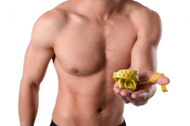Homem forte com corpo musculoso mantém a fita métrica amarela na mão