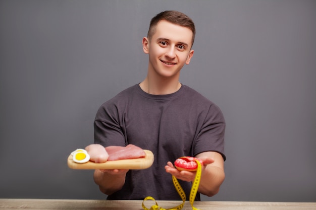 Homem forte consome uma refeição rica em proteínas, com carne e donuts.