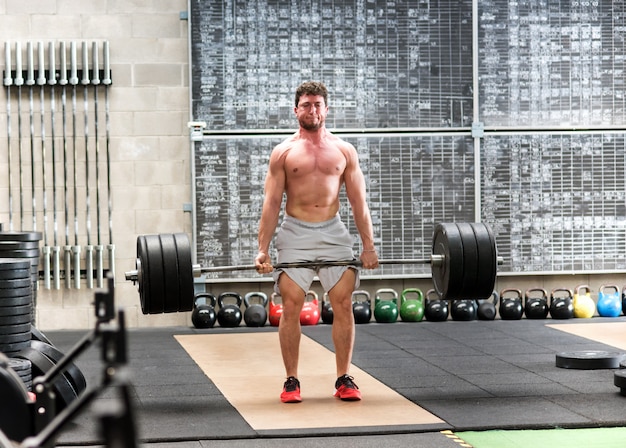 Homem forte deadlifter treinando com pesos pesados