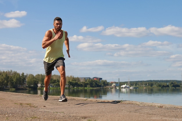 Foto homem forte esporte correndo enquanto trabalhava perto das margens do rio da cidade.